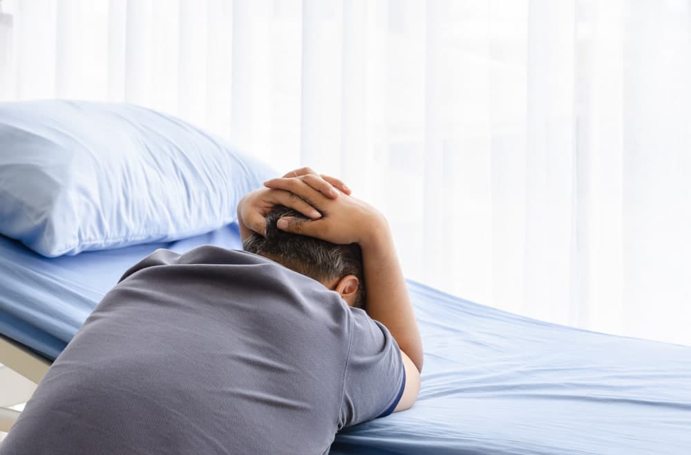 grieving person sitting beside a hospital bed