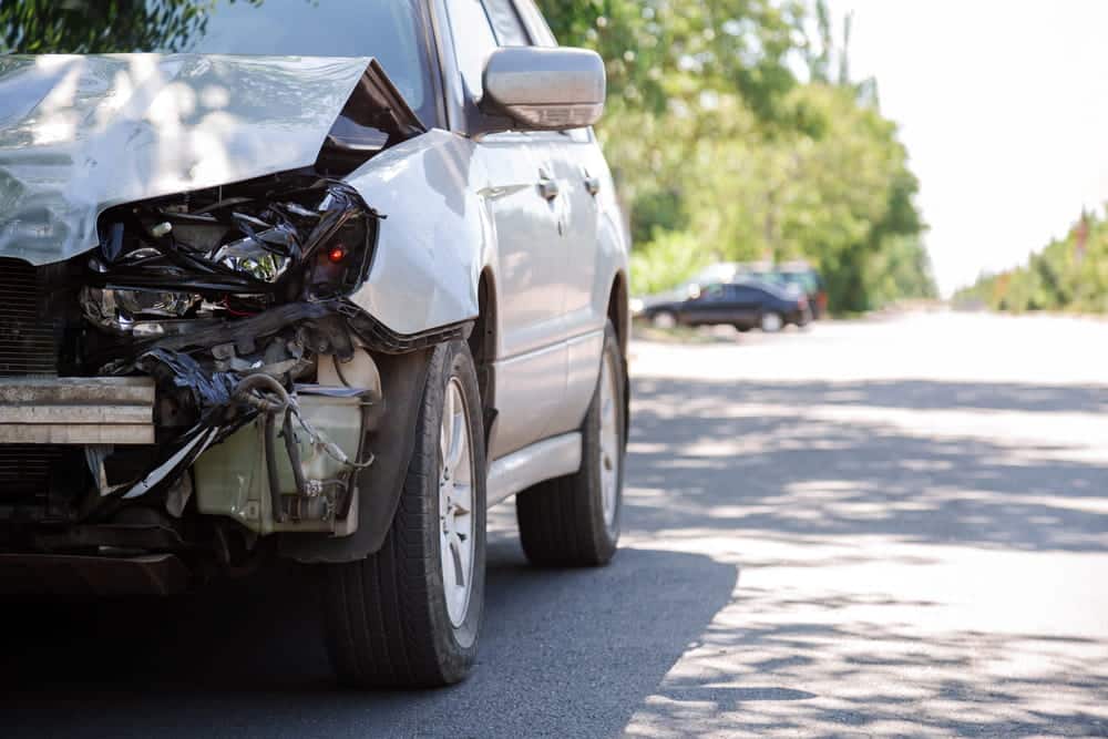 A damaged white car parked after a crash the streets